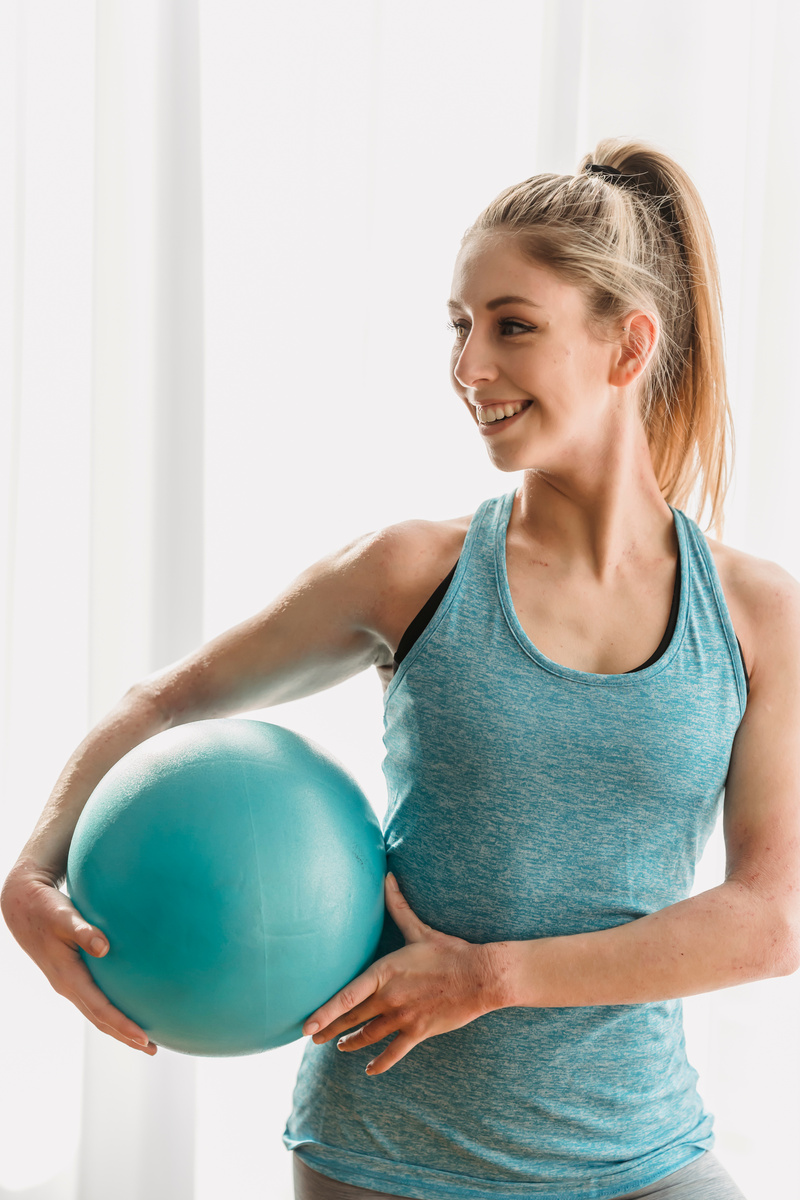 Happy fit woman exercising with rubber ball